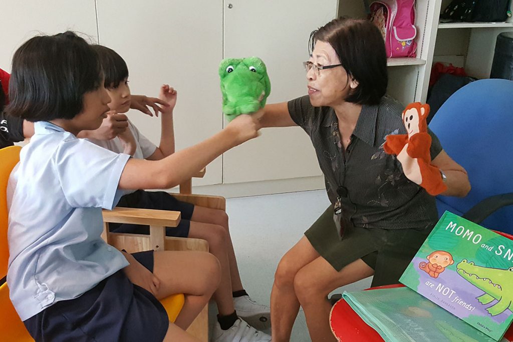 2 kids watching an AWWA staff with alligator and monkey puppet
