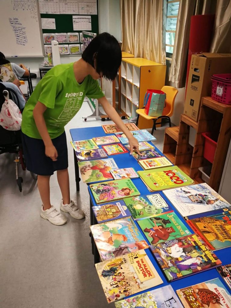A kid pointing and selecting a children's book