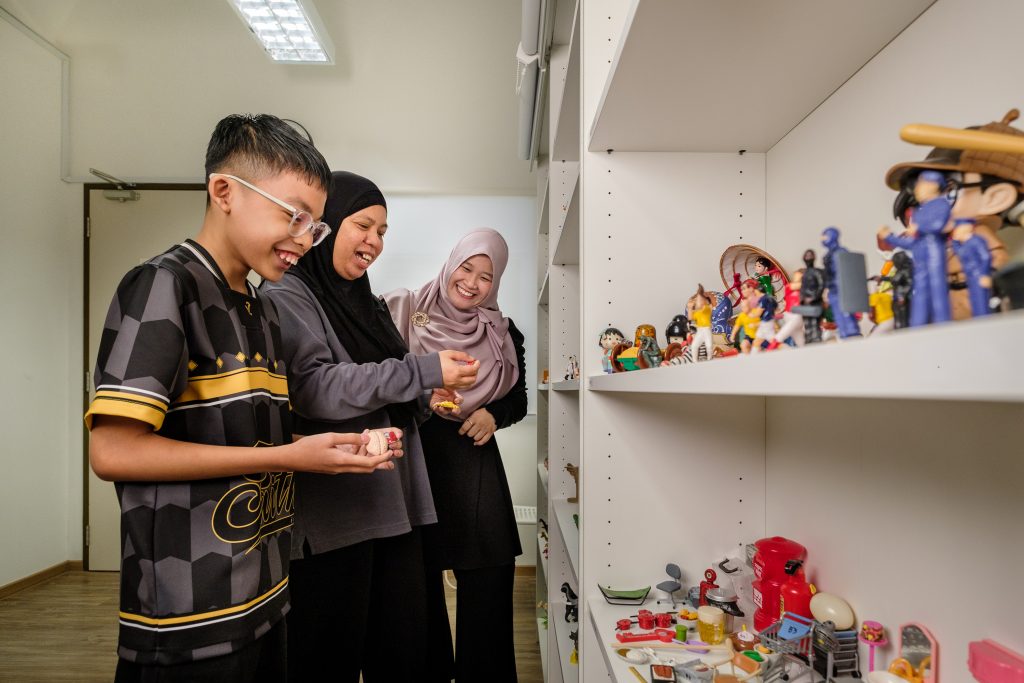 2 ladies with a boy standing infront of a rack display with toys and action figures